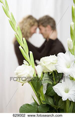 A couple embracing behind a bouquet of white sword lilies and roses View Large Photo Image Stock Image - A couple embracing behind a bouquet of white sword lilies and roses. Fotosearch