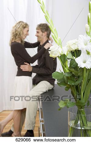 A couple embracing behind a bouquet of white sword lilies and roses View Large Photo Image Stock Photograph - A couple embracing behind a bouquet of white sword lilies and roses. Fotosearch