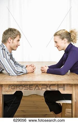 Stock Photograph - A couple sitting across from each other and smiling. Fotosearch