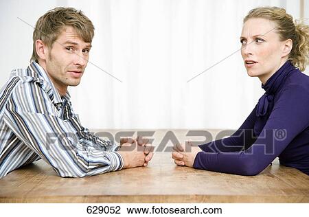 Stock Image - A couple sitting opposite each other at a table. Fotosearch