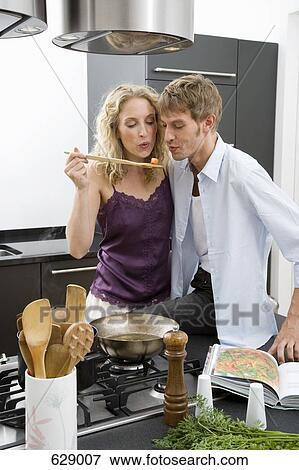 A couple tasting food from a pan View Large Photo Image Stock Photo - A couple tasting food from a pan. Fotosearch