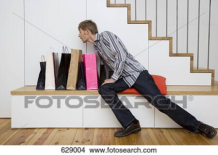 Picture - A man peeking in shopping bags. Fotosearch