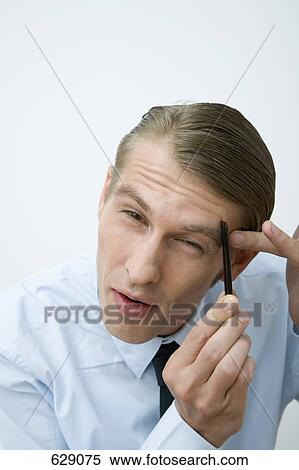 A mid adult man combing his eyebrow View Large Photo Image Stock Photography - A mid adult man combing his eyebrow. Fotosearch