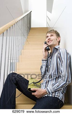 A mid adult man sitting on a staircase on the phone View Large Photo Image Stock Photo - A mid adult man sitting on a staircase on the phone. Fotosearch