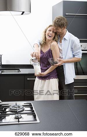 A mid adult man with his arms around a mid adult woman holding an electric mixer View Large Photo Image Stock Photo - A mid adult man with his arms around a mid adult woman holding an electric mixer. Fotosearch