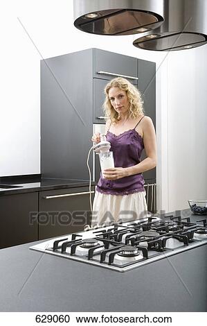 A mid adult woman standing in a domestic kitchen holding an electric mixer View Large Photo Image Stock Image - A mid adult woman standing in a domestic kitchen holding an electric mixer. Fotosearch