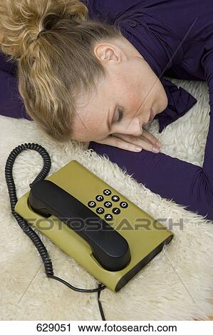Stock Image - A woman asleep next to a landline phone. Fotosearch