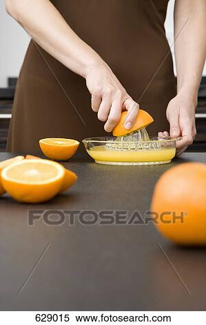 Stock Photography - A woman juicing oranges. Fotosearch