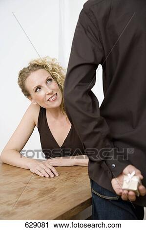 A woman peeking at the present in a man's hands View Large Photo Image Stock Image - A woman peeking at the present in a man's hands. Fotosearch
