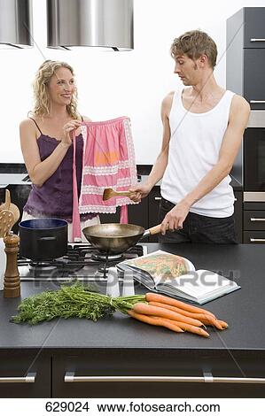 Picture - A woman showing a pink apron to a man. Fotosearch