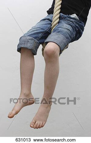 Stock Image - A child sitting on a rope swing. Fotosearch
