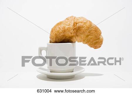 A croissant stuck in a coffee cup on a saucer View Large Photo Image Picture - A croissant stuck in a coffee cup on a saucer. Fotosearch