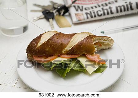 Stock Image - A submarine sandwich with tomato, lettuce and cheese on a plate with a bite out of it. Fotosearch