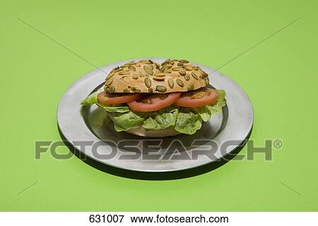 A Sunflower seed bagel sandwich with tomato and lettuce on a silver plate View Large Photo Image Stock Photo - A Sunflower seed bagel sandwich with tomato and lettuce on a silver plate. Fotosearch
