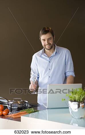 A man using a laptop and preparing to cook View Large Photo Image Stock Image - A man using a laptop and preparing to cook. Fotosearch