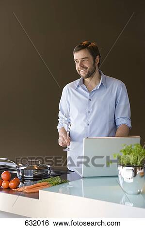 A man using a laptop and preparing to cook View Large Photo Image Stock Photograph - A man using a laptop and preparing to cook. Fotosearch