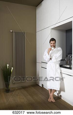 A smiling man in a bathrobe holding a coffee cup View Large Photo Image Stock Photo - A smiling man in a bathrobe holding a coffee cup. Fotosearch