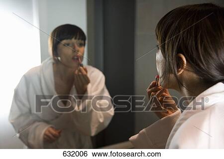 a woman applying lip gloss in a mirror View Large Photo Image Stock Photograph - a woman applying lip gloss in a mirror. Fotosearch