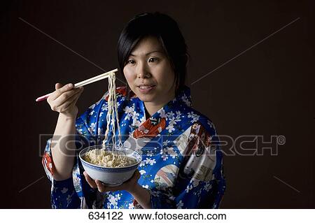 A woman dressed in a kimono eating noodles View Large Photo Image Stock Image - A woman dressed in a kimono eating noodles. Fotosearch