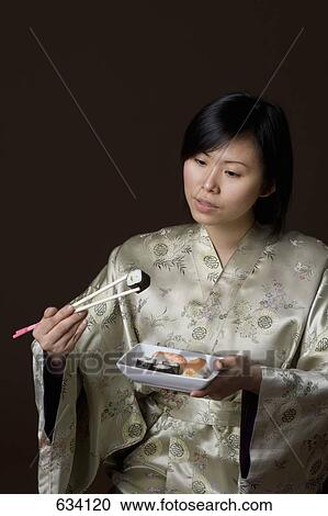 A woman dressed in a kimono eating sushi View Large Photo Image Stock Image - A woman dressed in a kimono eating sushi. Fotosearch