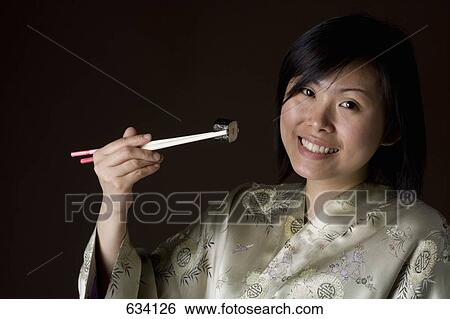 A woman in a kimono eating sushi View Large Photo Image Stock Photograph - A woman in a kimono eating sushi. Fotosearch