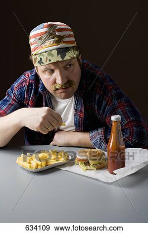 Stock Photo - Stereotypical American man eating a fast food meal. Fotosearch