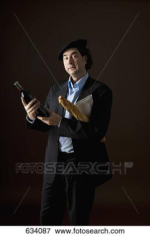 Stereotypical French man holding a bottle of wine, baguette and a newspaper View Large Photo Image Stock Photo - Stereotypical French man holding a bottle of wine, baguette and a newspaper. Fotosearch