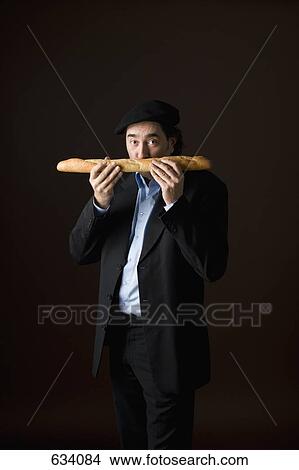 Picture - Stereotypical French man smelling a baguette. Fotosearch