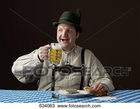 Stock Image - Stereotypical German man holding a beer and a pretzel. Fotosearch