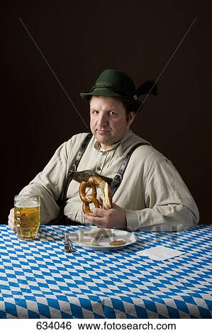 Stereotypical German man in Bavarian costume wiping mouth at a table with a beer and German meal View Large Photo Image Stock Photograph - Stereotypical German man in Bavarian costume wiping mouth at a table with a beer and German meal. Fotosearch