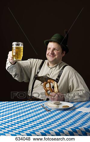 Stereotypical German Man toasting a glass of beer and holding a pretzel View Large Photo Image Stock Photo - Stereotypical German Man toasting a glass of beer and holding a pretzel. Fotosearch