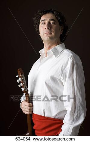 Stereotypical Spanish man in traditional clothing holding an acoustic guitar View Large Photo Image Picture - Stereotypical Spanish man in traditional clothing holding an acoustic guitar. Fotosearch