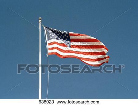 An American flag flying against a clear blue sky View Large Photo Image Stock Image - An American flag flying against a clear blue sky. Fotosearch
