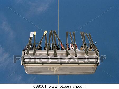 Stock Image - Low angle view of skiers sitting on a ski lift. Fotosearch