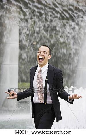 A businessman listening to an mp3 player and singing View Large Photo Image Stock Image - A businessman listening to an mp3 player and singing. Fotosearch