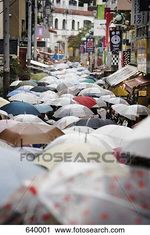 Stock Image - A street in Japan crowded with people carrying umbrellas. Fotosearch
