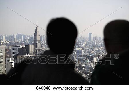 Stock Image - Two people looking at view of Tokyo skyline. Fotosearch