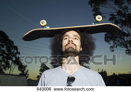 A man balancing a skateboard on his head View Large Photo Image Stock Photograph - A man balancing a skateboard on his head. Fotosearch