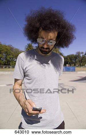 A man using his mobile phone in a skate park View Large Photo Image Stock Image - A man using his mobile phone in a skate park. Fotosearch