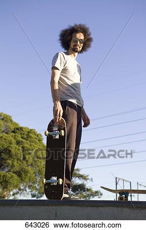 A skateboarder standing at the top of a ramp View Large Photo Image Stock Photograph - A skateboarder standing at the top of a ramp. Fotosearch