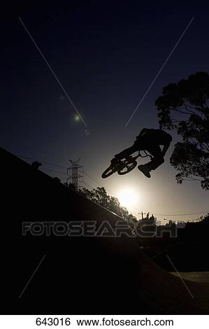 Silhouette of a person doing a stunt on a BMX bicycle View Large Photo Image Stock Photograph - Silhouette of a person doing a stunt on a BMX bicycle. Fotosearch
