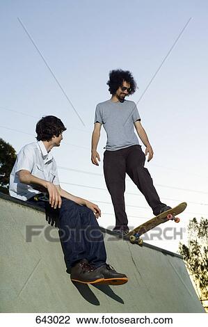 Stock Image - Two skateboarders at the top of ramp. Fotosearch