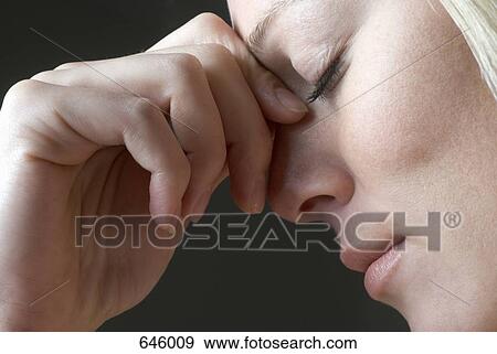 Stock Photo - A woman squeezing the bridge of her nose. Fotosearch