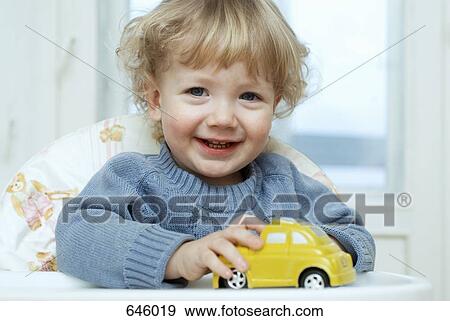 A young boy sitting in a high chair playing with a toy car View Large Photo Image Stock Photo - A young boy sitting in a high chair playing with a toy car. Fotosearch