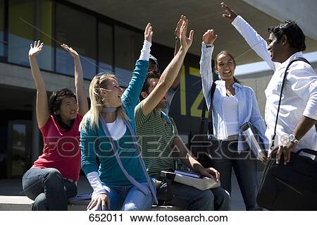 Stock Image - University students raising their hands at a meeting on campus. Fotosearch