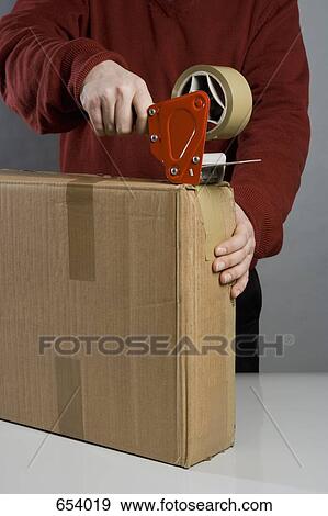Stock Photo - A man taping a cardboard box. Fotosearch