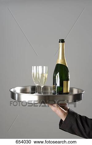 A waiter carrying a tray with a champagne bottle and glasses View Large Photo Image Stock Image - A waiter carrying a tray with a champagne bottle and glasses. Fotosearch