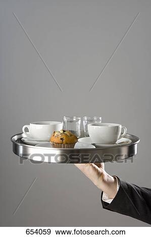 A waiter holding a tray with coffee cup and muffin View Large Photo Image Stock Photo - A waiter holding a tray with coffee cup and muffin. Fotosearch