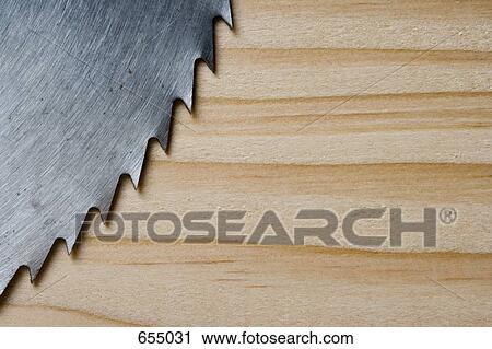 Stock Image - Circular saw blade and wood plank, extreme close-up. Fotosearch