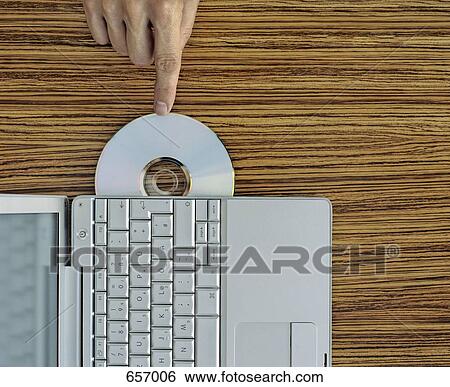 A hand pushing a CD into a laptop View Large Photo Image Stock Photograph - A hand pushing a CD into a laptop. Fotosearch